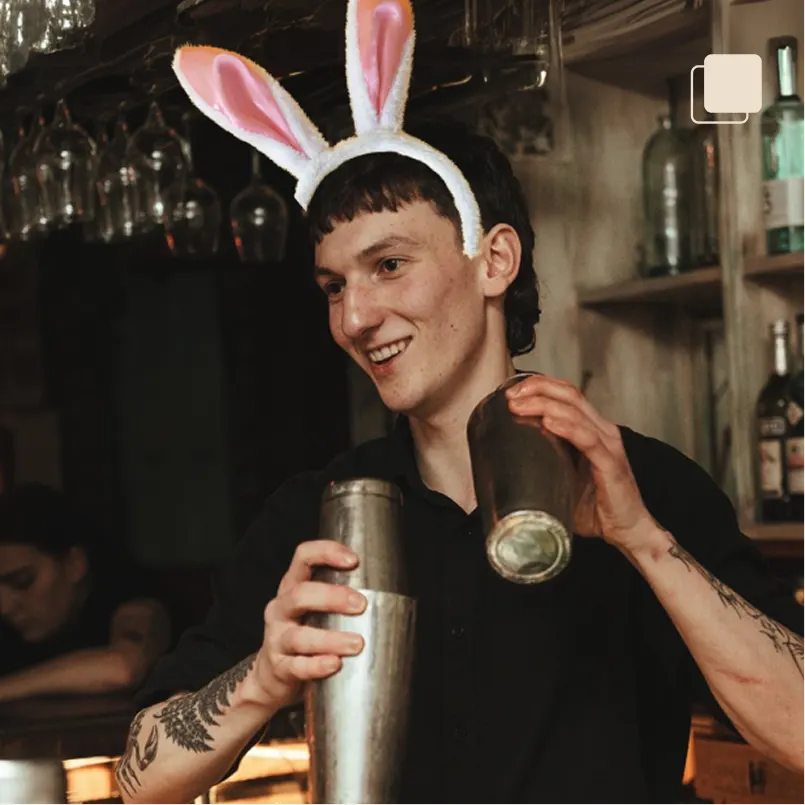 A member of smokestack fuck & soul bar staff making cocktails wearing bunny ears