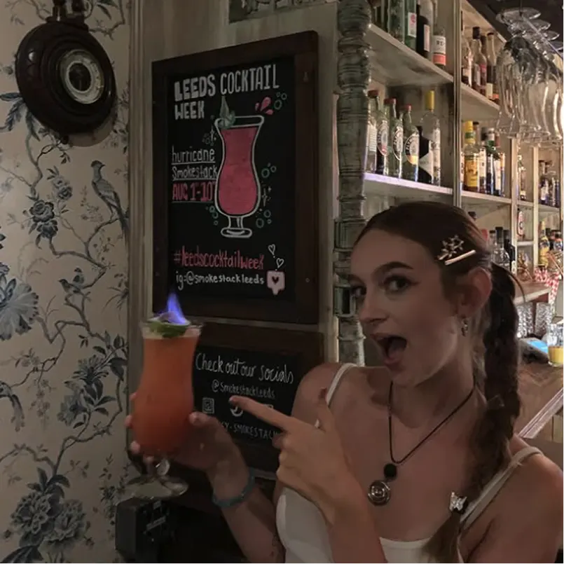 A member of smokestack bar staff holding a flaming cocktail